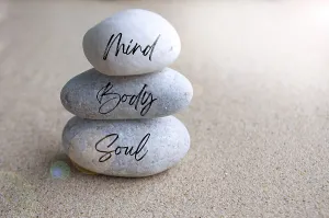 Mind, body and soul text on zen stones with bright shining light