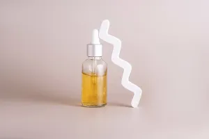 A minimalist shot of a skincare serum in a glass dropper bottle with golden liquid
