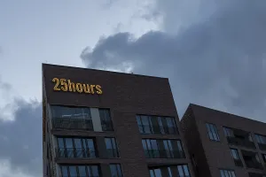 Modern architecture, neon sign on the facade of the 25hours Hotel in front of a cloudy sky at dusk