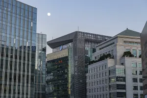 Modern buildings with glass facades under an evening sky with a moon