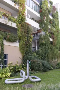 Modern facade with lush greenery and a sculpture in the front garden