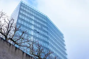 Modern Glass Building with Bare Tree and Sky with Clouds in a Sunny Autumn Day in Neuchatel