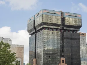 Modern high-rise building with glass facade and unique architecture under a clear sky