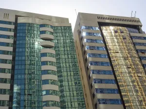 Two modern high-rise buildings with reflective glass facades in the sunlight