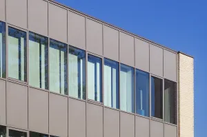 Modern office building exterior showcasing a contemporary design with large windows reflecting the vibrant blue sky