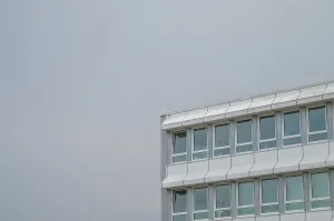 Modern office building exterior showcasing glass windows and a grey sky background