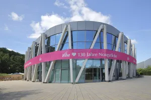 Modern round building with glass window and pink banner with inscription