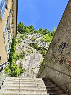 Modern stone staircase leads to a green rock under a clear sky