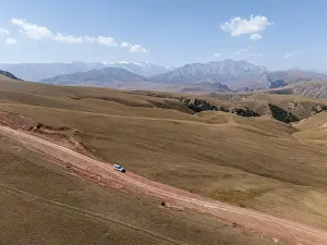 Moldo-Ashuu Pass, car on road between yellow hills