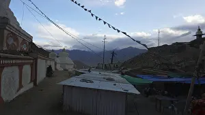 Monastery structures under a blue sky decorated with prayer flags