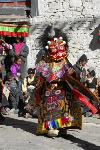 Monk wears fearful and red mask and dress of a demon at festival in colourful decorated Rongbuk Monastery Tibet China