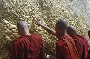 Monks attaching gold leaf to the Golden Rock