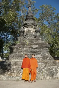 Two monks in orange robes in front of a stupa