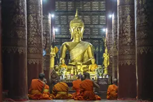 Category Buddhism Prints: Monks praying in front of the great Buddha in the temple Wat Pak Khan Khammungkhun