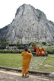 Monks taking a photograph of a Buddha image on a cliff