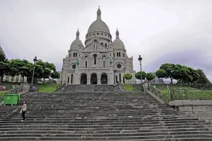 Monumental stairs lead to a large basilica under a cloudy sky