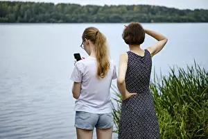 Mother and daughter have come to the shore of the lake and are exploring the surroundings