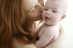 Mother kissing little baby smiling on white background