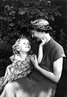 A mother is sitting on a park bench with her daughter