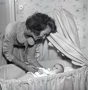Motherhood in the 1950s. A mother is cuddling with her baby at home