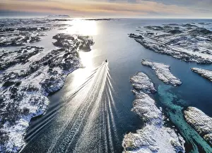 Category Scandinavia Prints: Motorboat sailing through a winter fjord landscape with small islands