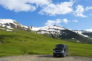 A motorhome stands in front of a green