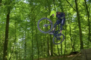 Mountain biker, downhill biker jumps over a ramp on a downhill trail