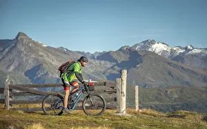 Mountain biker, late 40s, rides eMTB on single trail in the autumnal mountain landscape of the Stubaier Alps