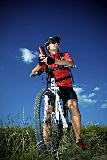 Mountain biker taking a break, holding water bottle