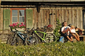 Mountain bikers resting in front of an old farmhouse on Kraftalm alp