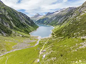 A mountain lake embedded in an alpine landscape with green meadows