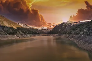 Mountain lake at sunset with dramatic clouds and orange sky