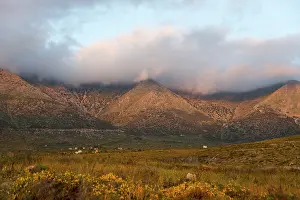 Mountain landscape at dusk with clouds enveloping the peaks in a tranquil rural setting