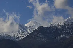 Mountain peaks with snow and clouds under a blue sky