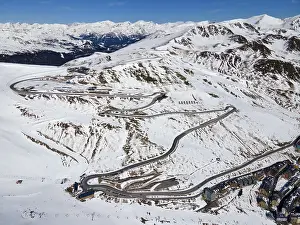 Mountain road with serpentines through a snowy mountain landscape with traffic