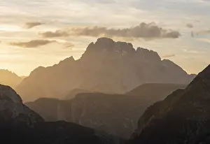 Framed Print : Mountain silhouette during sunset with dramatic clouds and warm light in alpine terrain