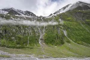 Mountain streams flow over steep mountain slopes into the tagl of the Schlegeisgrund