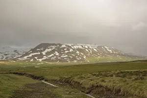 Mountain with sunlight in bad weather near Miklavatn