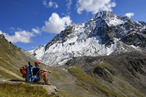 Mountaineer with backpack on stone and Sellrain mountains in the background