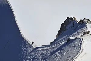 A mountaineer climbs over a snow-covered mountain ridge