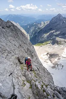 Mountaineer with helmet climbing in a secured via ferrata