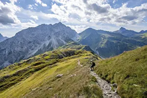 Mountaineer on a hiking trail on a grassy mountain ridge