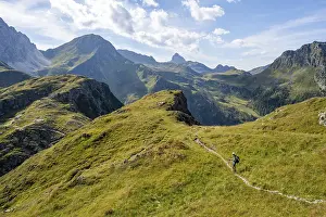 Mountaineer on a hiking trail on a grassy mountain ridge