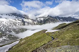 Mountaineer on hiking trail, mountain panorama with high fog in the valley
