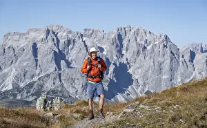 Mountaineer on hiking trail in front of rocky mountain peaks