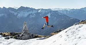 Mountaineer jumping, next to a cairn