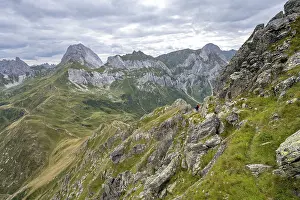 Mountaineer on a narrow hiking trail on a steep meadow slope