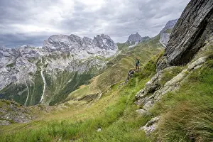 Mountaineer on a narrow hiking trail on a steep meadow slope