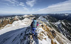 Mountaineer on the narrow rocky snowy ridge of the Ammergauer Hochplatte