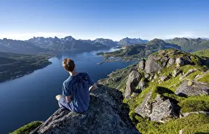 Mountaineer sitting on the summit of Dronningsvarden or Stortinden